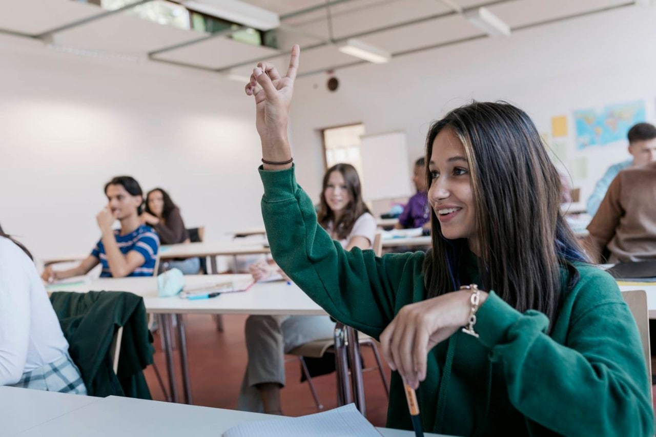AI in Education Young girl raising hand and smiling in classroom